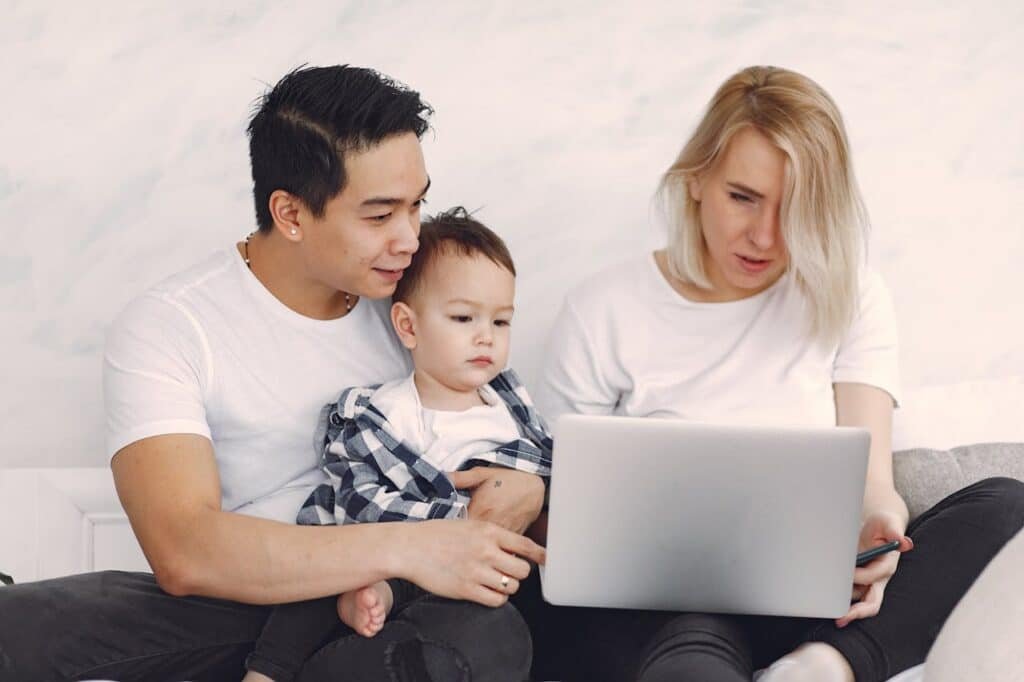 Young family enjoying quality time together, engaging with a laptop indoors.